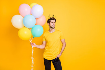 Photo of handsome boast guy holding air balloons golden crown on head shows high social status wear...