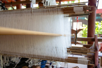 Selective focus of cotton thread on weaver machine. Thai cotton handmade. Homespun fabric process. The process of fabric weaving in vintage weaver machine.