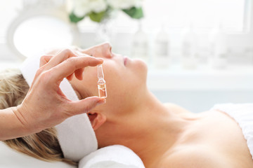 Professional care in a beauty salon. The beautician applies a cosmetic preparation in an ampoule
