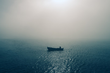 Fishing boat and fisherman in the sea, foggy morning over the water - Powered by Adobe