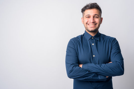Portrait of happy young Persian businessman smiling with arms crossed
