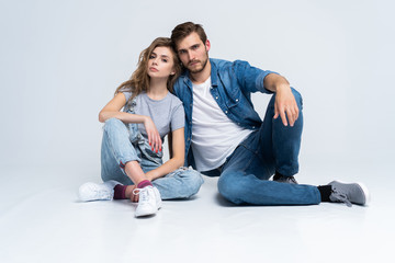 Fototapeta na wymiar Portrait Of Happy Young Couple Sitting On Floor Leaning Against Wall