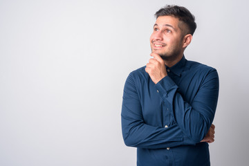 Portrait of happy young handsome Persian businessman thinking