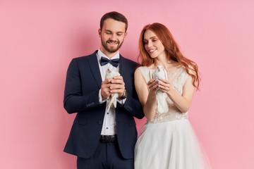 Attractive woman with red hair and man wearing tuxedo holding pigeons in hands, happy together,...