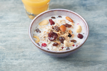 Bowl of granola with milk, nuts, raisins and cranberries. Concept for a tasty and healthy meal. Rustic wooden background. Close up.