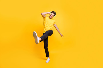 Fototapeta na wymiar Full length body size view of his he nice attractive funny funky cheerful cheery teenage guy having fun time listening music strolling isolated over bright vivid shine vibrant yellow color background