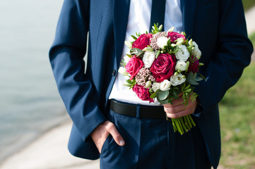 Colorfull bouquet of flowers in the hands of groom