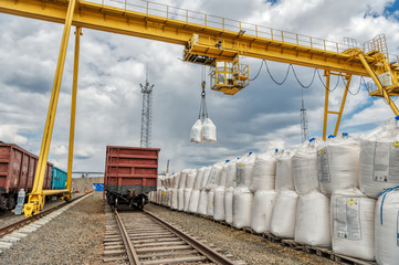 Cargo crane lifts two large bags of ammonium nitrate. Big yellow gantry crane.