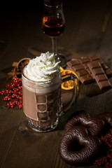 Heiße, dunkle Russische Trinkschokolade zu Weihnachten mit Sahne, Rum, Lebkuchen, Schokoladentafel, Gewürzen, Glitzer Schneeflocken rot auf dunkel Holz Hintergrund 