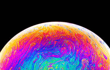 Rainbow soap bubble on a dark background. Close-up of colorful surface.