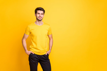 Photo of serious dreamy man standing confidently with hands in pockets looking into camera next to empty space isolated over vibrant color background