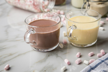 Zubereitung von heißer, dunkle und weiße Trinkschokolade mit Milch, Kakaopulver und Marshmellows auf Marmor hell Hintergrund 