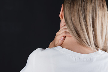 Portrait of a girl who holds on to the neck with hands experiencing pain.