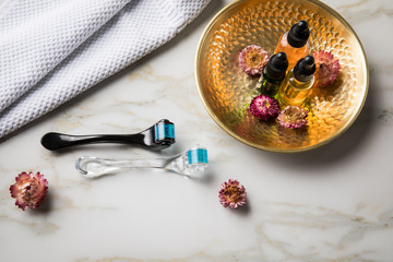 Dermaroller, Handtuch und Beauty Naturkosmetik Serum Öl Flasche zum  Microneedling für Anti Aging Lifting oder Akne Anwendung auf Marmor Hintergrund