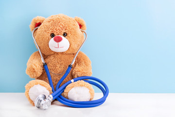 Teddy bear with stethoscope on blue background with space to copy; concept fun Pediatrics; children's medicine - obrazy, fototapety, plakaty