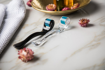 Dermaroller, Handtuch und Beauty Naturkosmetik Serum Öl Flasche zum  Microneedling für Anti Aging Lifting oder Akne Anwendung auf Marmor Hintergrund