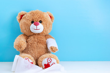 Teddy bear with bandaged hand on blue background with space to copy; concept fun Pediatrics; children's medicine