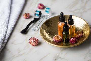 Dermaroller, Handtuch und Beauty Naturkosmetik Serum Öl Flasche zum  Microneedling für Anti Aging Lifting oder Akne Anwendung auf Marmor Hintergrund
