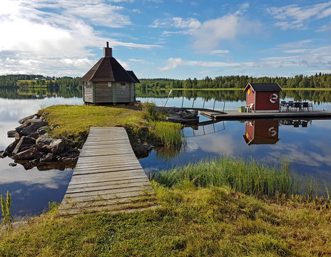 Swedish lake Gaxsjon with reflections on the calm water and a sauna house on the islet