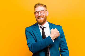 young red head businessman feeling happy, positive and successful, motivated when facing a...