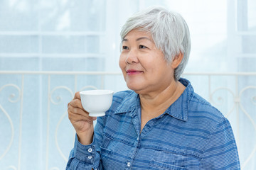 Happy senior woman female enjoy drinking cup of coffee or tea at home