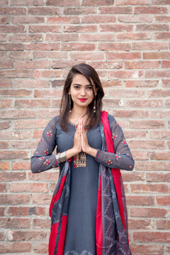 Smiling ethnic girl, hand in traditional indian mudra gesture stand , look at camera. Girl in traditional Indian clothing, salwar kameez. Girl traditional Indian decorations, bindi, chudiyan, jumka