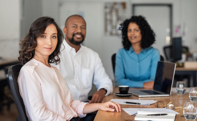 Confident diverse businesspeople sitting together at an office table