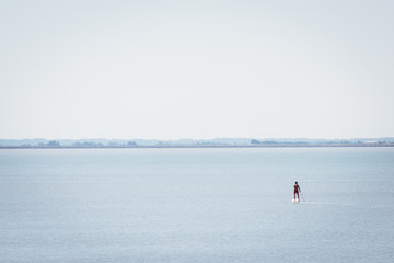 un homme sur un paddle sur l'eau. La mer et un homme pratiquant le paddle.
