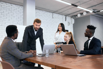 Demanding caucasian boss and his team working on one business project gathered to discuss problems on agenda