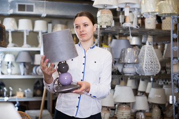 Positive woman is looking on modern lamps