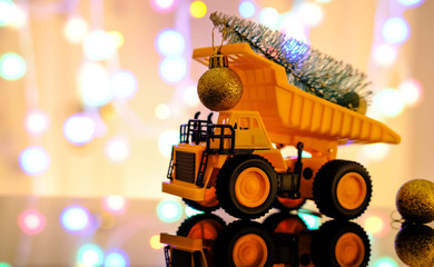Christmas card. Children's truck carries a Christmas tree. Bokeh, multicolor color. Light blurred background