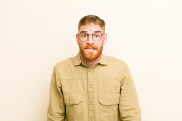 young red head man looking puzzled and confused, biting lip with a nervous gesture, not knowing the...