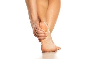 woman holding her painful heel on white background
