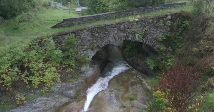 Drone Shot of montain river going under a stone bridge