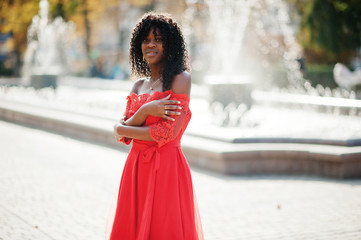 Stylish trendy afro france curly woman posed at autumn day in red dress. Black african female model...