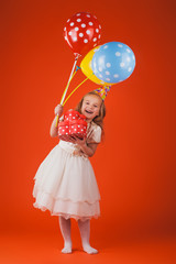 girl with gifts and balloons on an orange background. Studio portrait photos