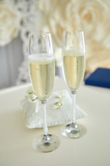 Two glasses of a champagne and pillow with wedding rings..