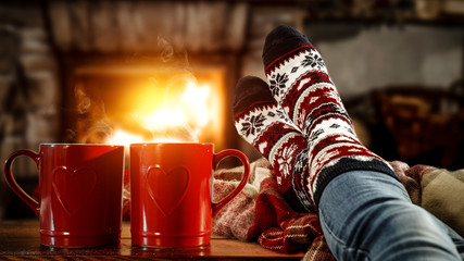 Woman legs with christmas socks and fireplace in home interior. 