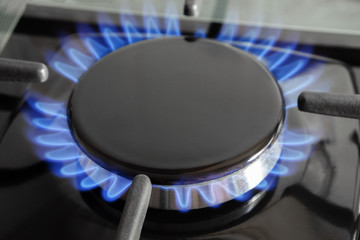 Blue flame on a black gas stove close-up.