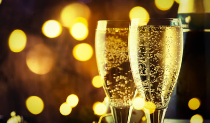 Two champagne glasses and christmas decoration on wooden snow golden bokeh background. Happy New Year Celebration. Selective focus and small depth of field