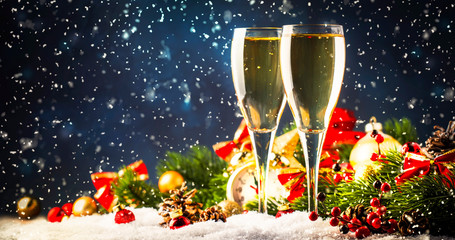 Two champagne glasses and christmas decoration over blue snow golden bokeh background. Happy New Year Celebration. Selective focus and small depth of field