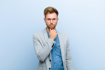 young businessman looking serious, confused, uncertain and thoughtful, doubting among options or...