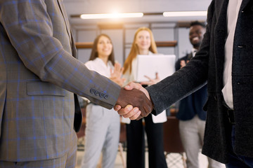 African and caucasian business partners shaking hands each other. Successful deal of business people