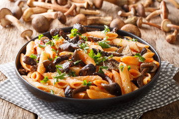 Italian hot pasta with roasted honey mushrooms, parmesan and tomato sauce close-up in a plate. horizontal