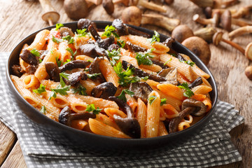 Rustic pasta with roasted honey mushrooms, parmesan and tomato sauce close-up in a plate on the table. horizontal
