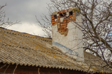 old brick chimney with fallen off stucco on a slate roof.