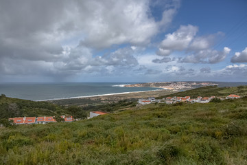 Fototapeta na wymiar View at the Nazare Village with touristic beach, atlantic ocean and sky