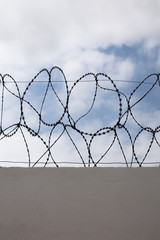 View of a barbed wire fence with cloudy blue sky as background