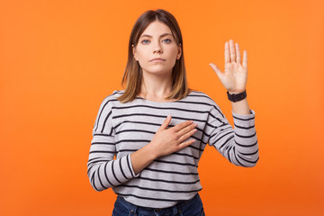 Portrait of faithful beautiful young woman with brown hair in long sleeve striped shirt standing,...