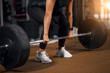 Fototapeta na wymiar Young active sporty woman trying to make deadlift as part of fitness program, in brightly lighted gym, active people, sport concept, side indoor shot